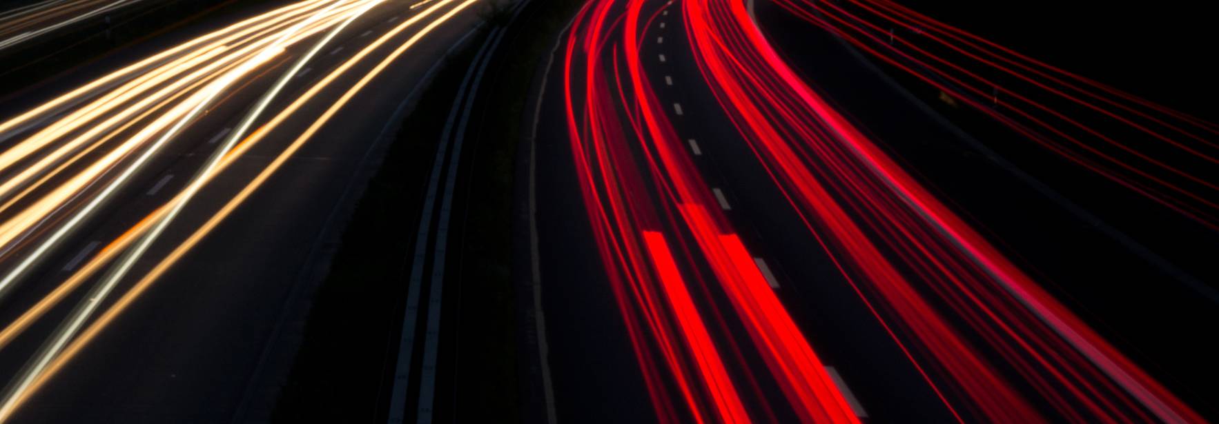 Una imagen que muestra el rastro de luces de los vehículos en movimiento sobre una carretera durante la noche.