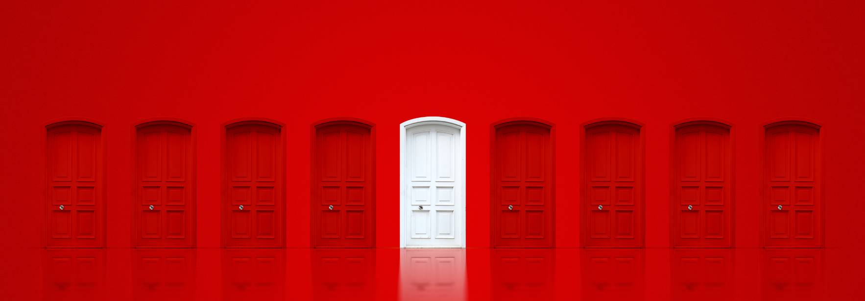 Una puerta blanca destaca entre varias puertas rojas en un fondo uniforme.