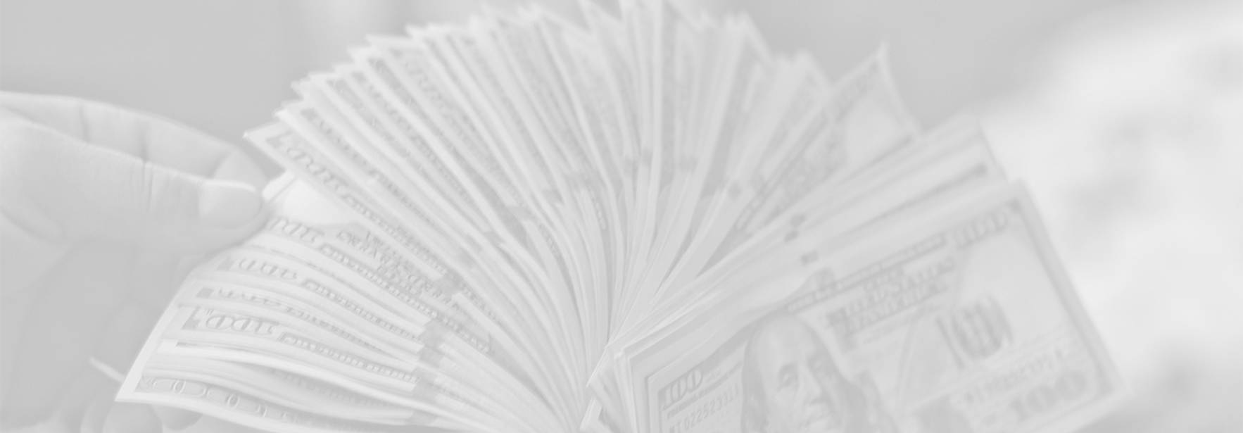 Una mano sostiene un fajo de billetes de cien dólares.