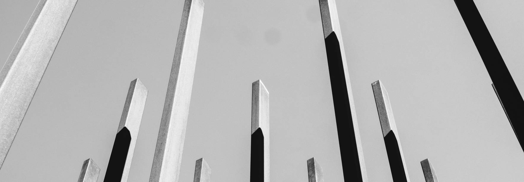 La imagen muestra una serie de postes verticales de diferentes tamaños en un fondo gris claro.