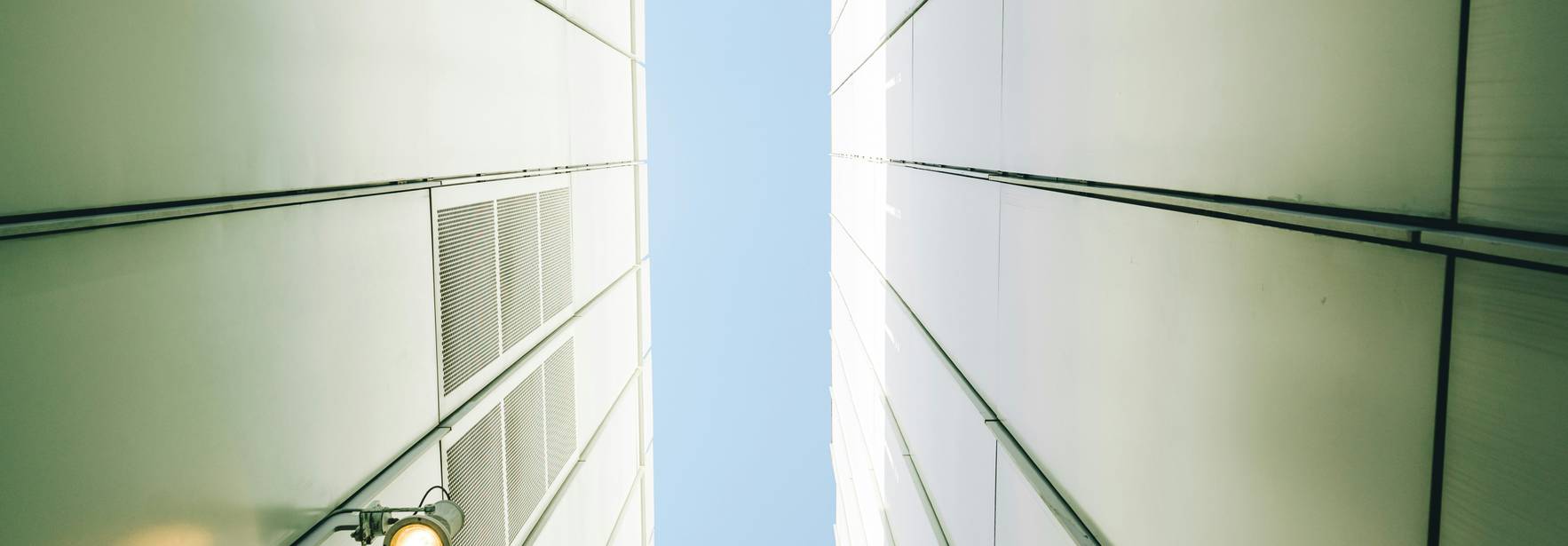 La imagen muestra una perspectiva desde el suelo hacia el cielo entre dos edificios altos y delgados.