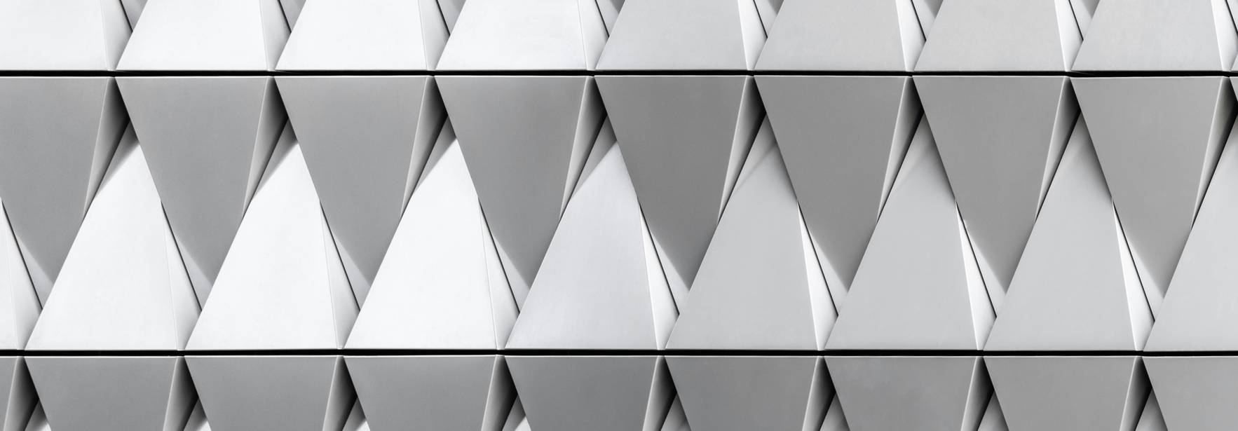 La imagen muestra un patrón geométrico en relieve compuesto de triángulos metálicos dispuestos en filas alternas.