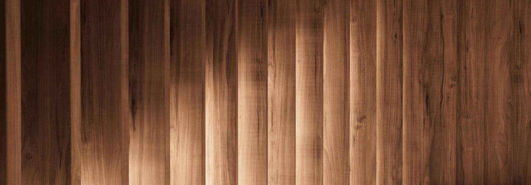 Una sala iluminada suavemente con columnas de madera que proyectan sombras alargadas en el suelo.