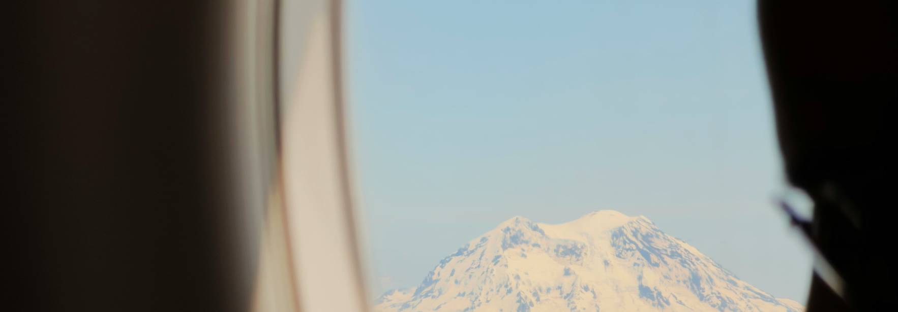 Se observa una montaña nevada a través de la ventanilla de un avión.