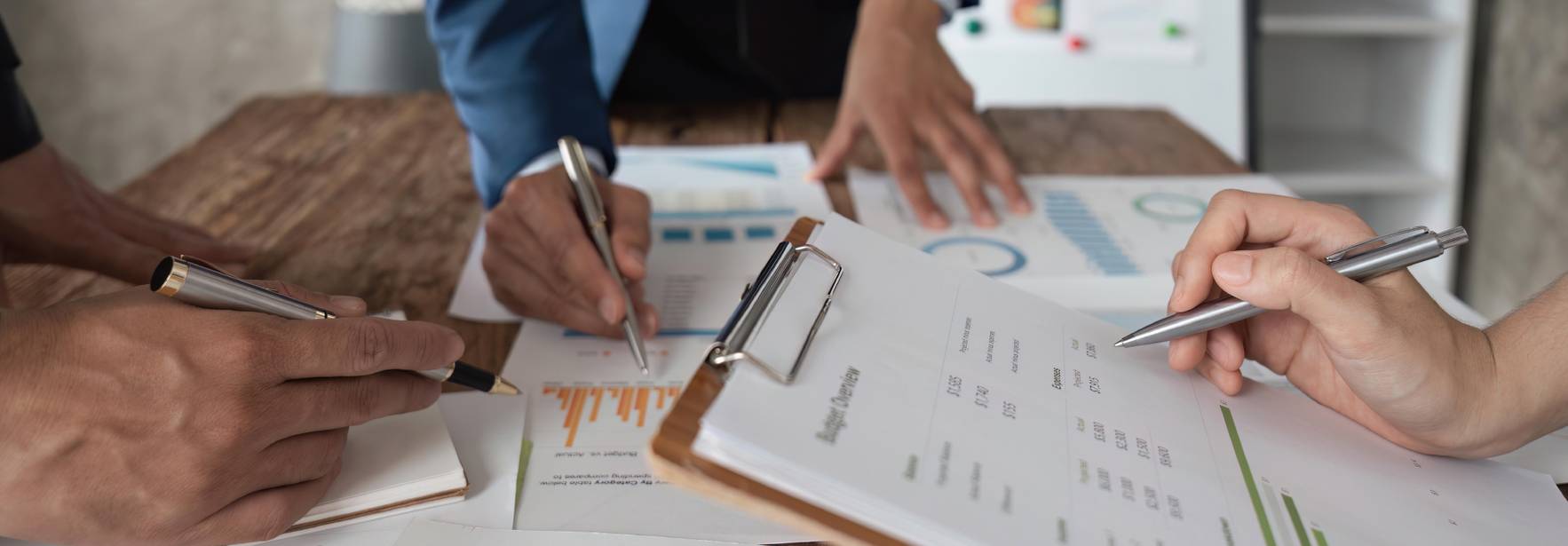 Una reunión de trabajo donde varias personas analizan gráficos y documentos sobre datos.