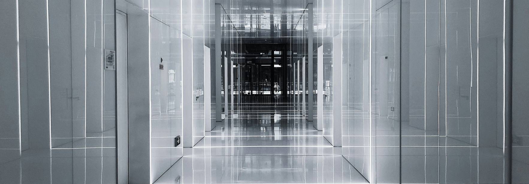 Un largo pasillo moderno con paredes blancas y luces integradas que crean un efecto futurista.