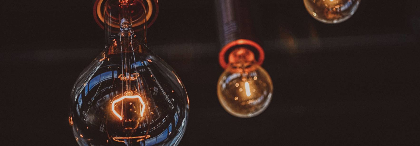 Tres bombillas colgantes iluminan un espacio con un diseño moderno y cálido.
