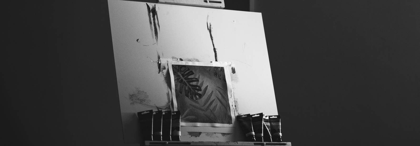 Una pintura en un caballete con tubos de pintura alrededor.