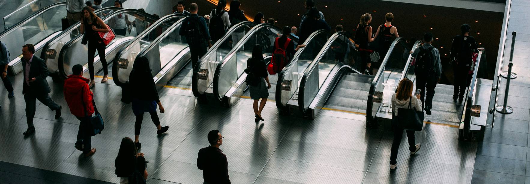 Una multitud de personas utiliza unas escaleras mecánicas en un edificio moderno.