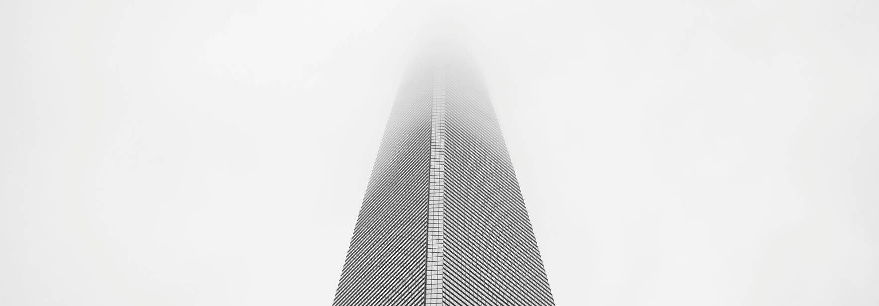 Una torre se eleva hacia el cielo, parcialmente oculta por la niebla.