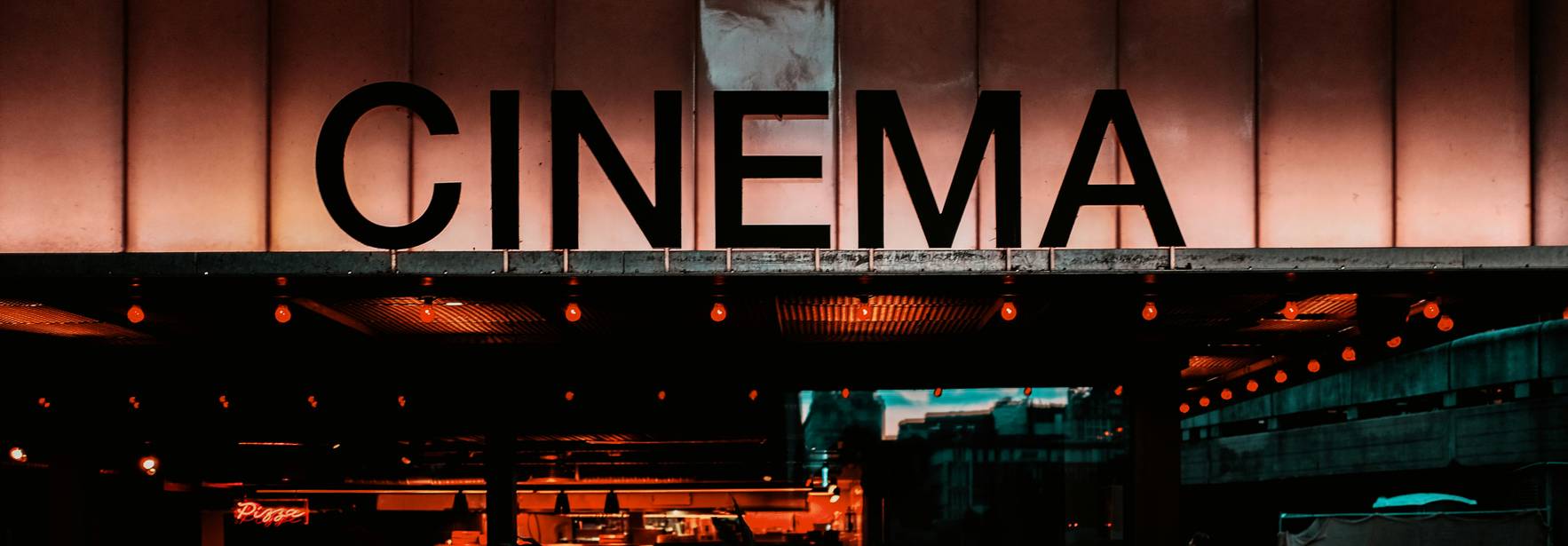Fachada de un cine iluminada con luces cálidas y el letrero que dice 'CINEMA'.