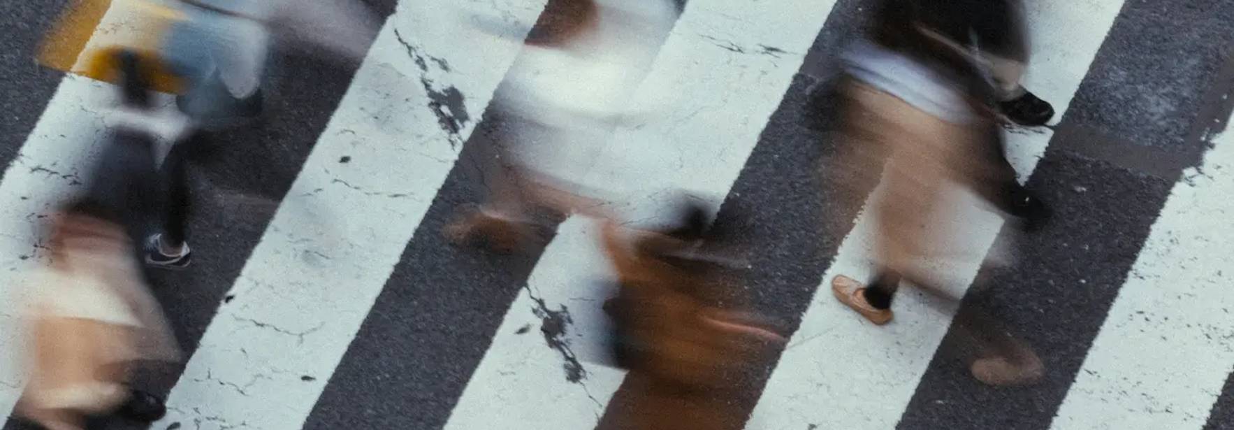 Una multitud se atraviesa por un paso peatonal en una calle urbana.