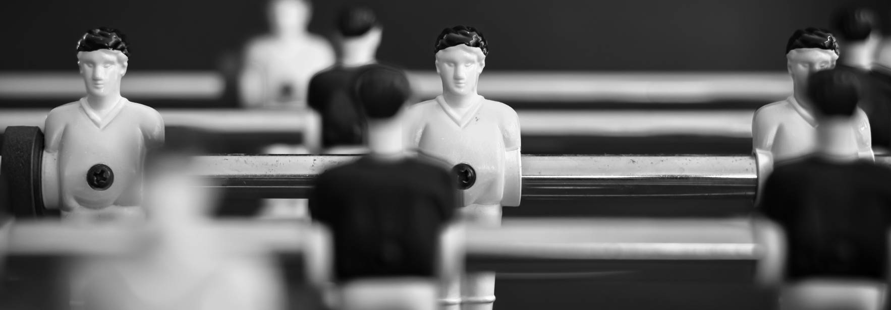 La imagen muestra un juego de futbolín con figuras en blanco y negro dispuestas en alineación.
