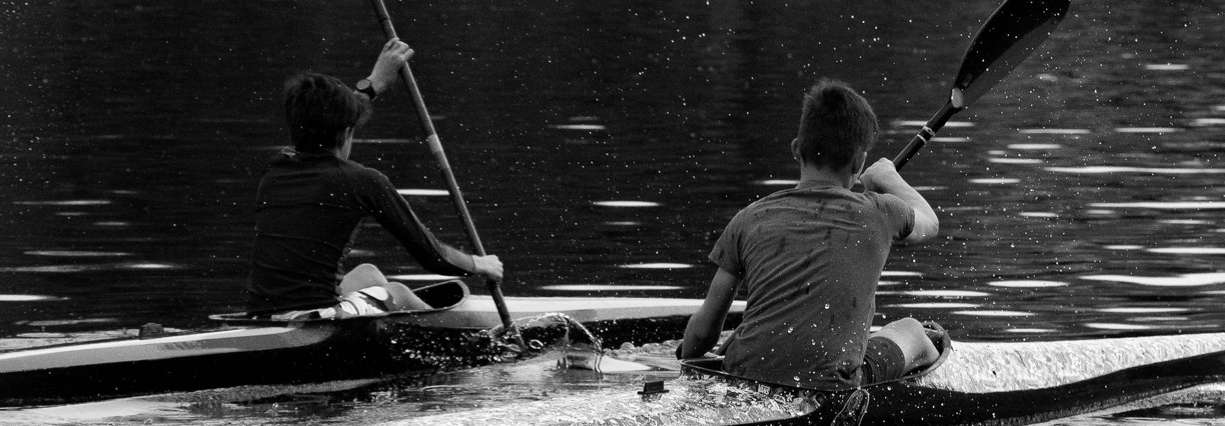 Dos personas remando en kayaks sobre un lago tranquilo.