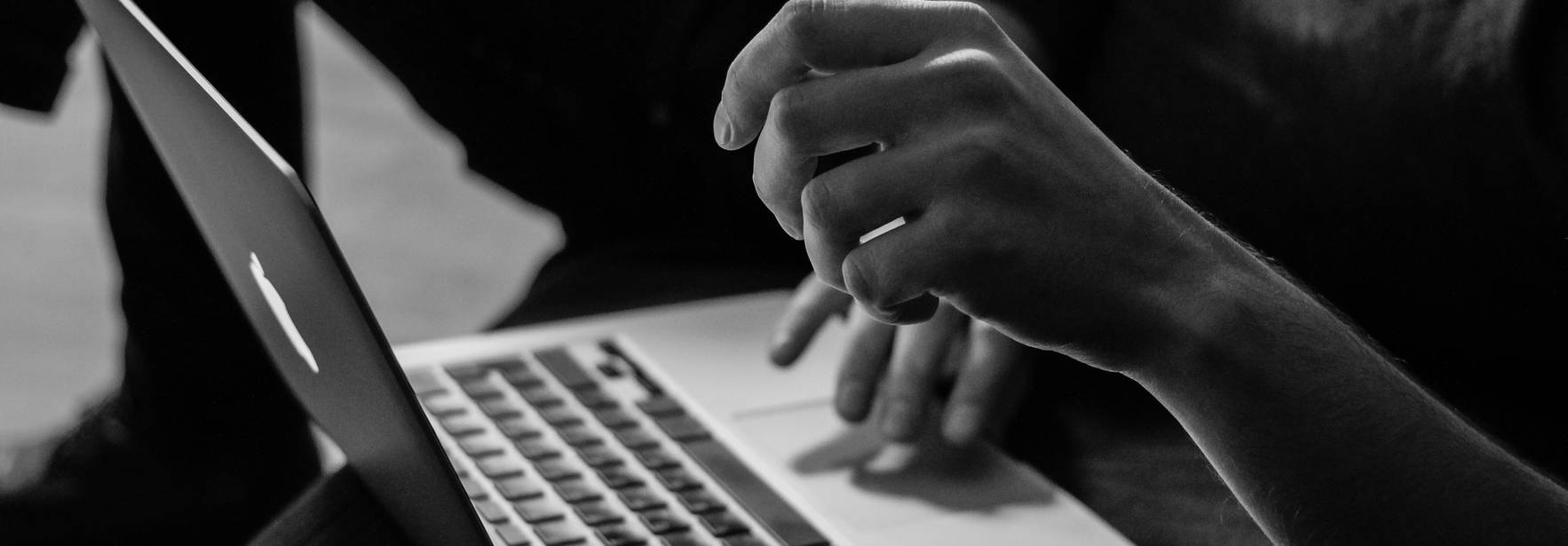 Una mano está tocando el teclado de una computadora portátil mientras la otra mano se sostiene en el aire.