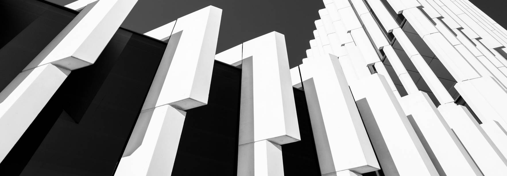 La imagen muestra una fachada moderna con paneles verticales en blanco y negro, creando un efecto arquitectónico impresionante.