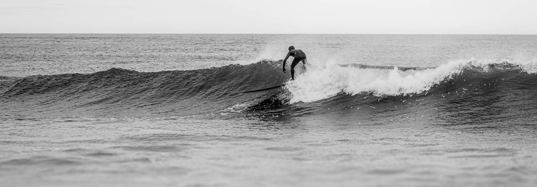 Un surfista monta una ola en una playa.