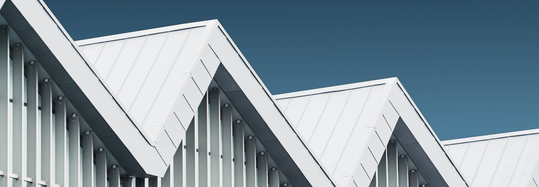 La imagen muestra un edificio con un diseño moderno y techos en forma de zigzag.