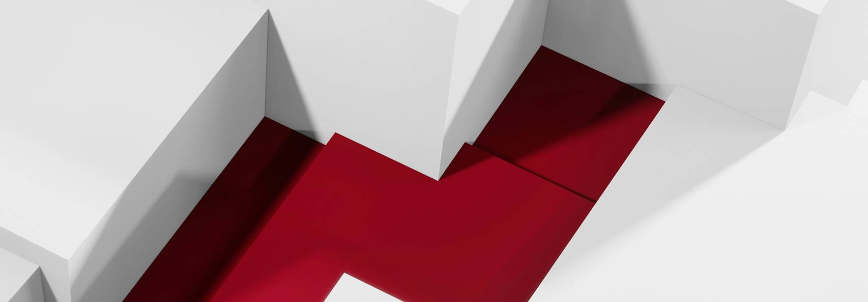 La imagen muestra un camino rojo que se abre paso entre estructuras blancas en un entorno minimalista.