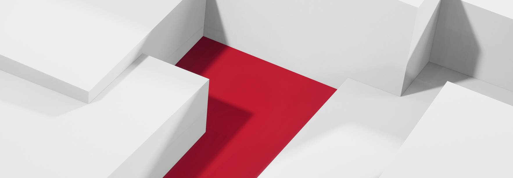 La imagen muestra un espacio arquitectónico minimalista con bloques blancos que encierran una franja roja en el centro.