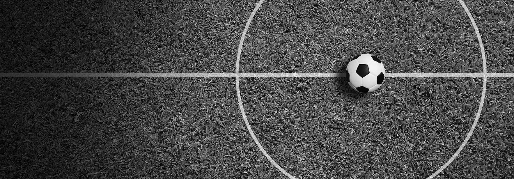 Una pelota de fútbol se encuentra en el centro de un campo de juego.