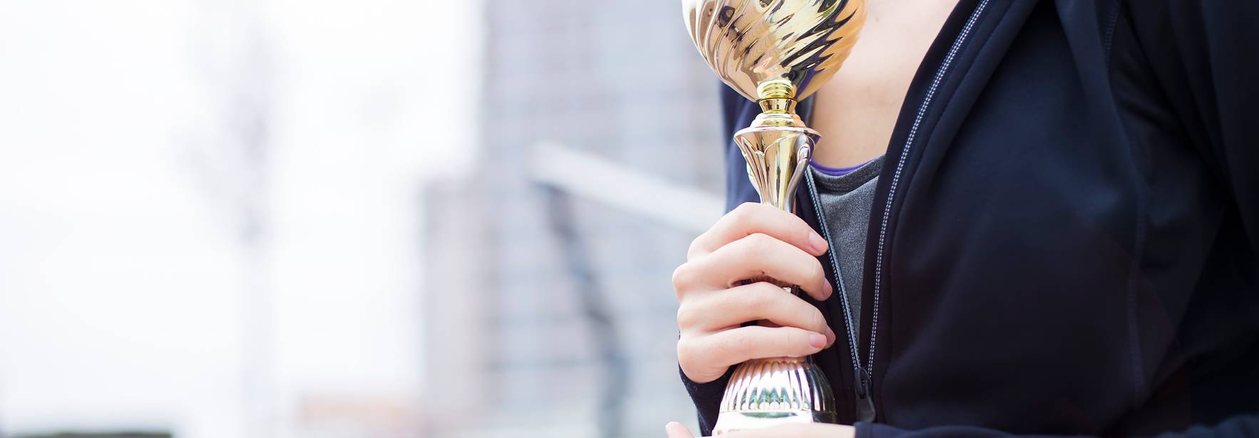 Una persona sosteniendo un trofeo en un entorno urbano.