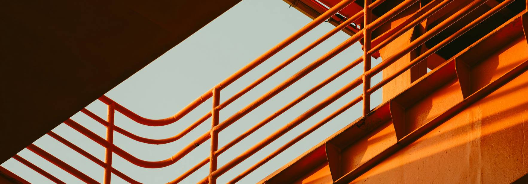 Una imagen abstracta que muestra líneas y sombras en tonos naranjas y un cielo azul en el fondo.