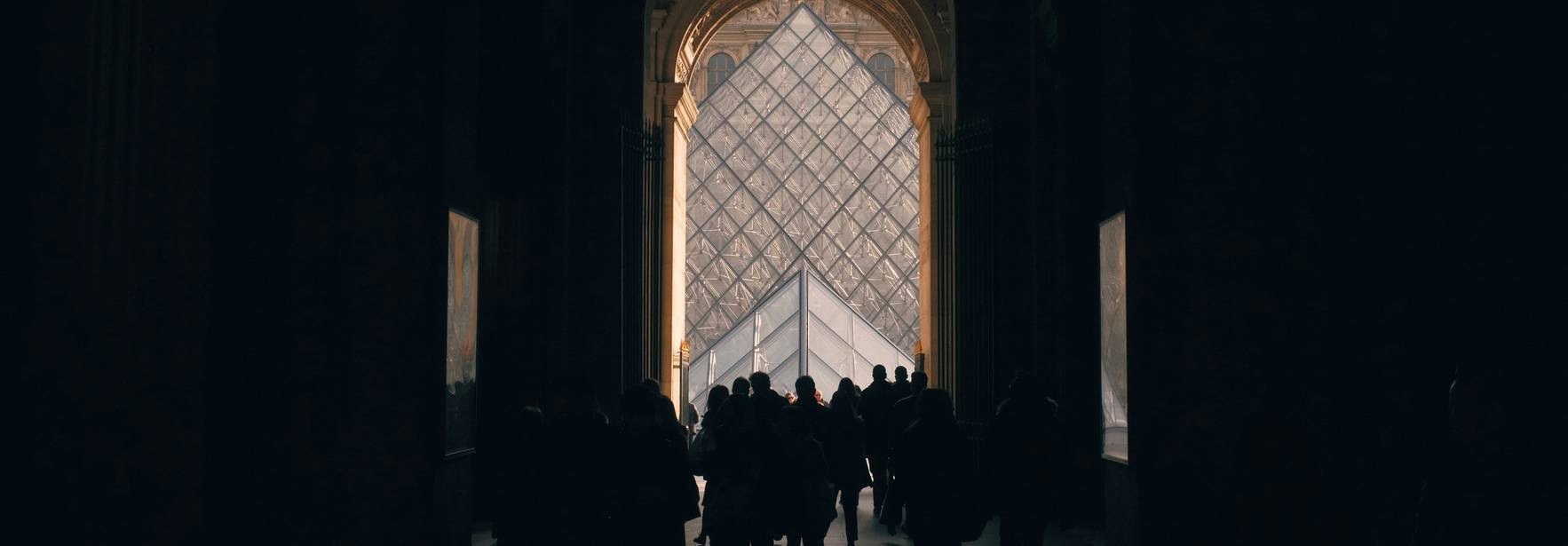 Un grupo de personas camina hacia una entrada iluminada en un edificio oscuro.