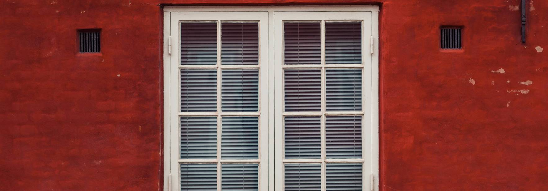 Una ventana blanca de madera sobre un fondo de pared roja.