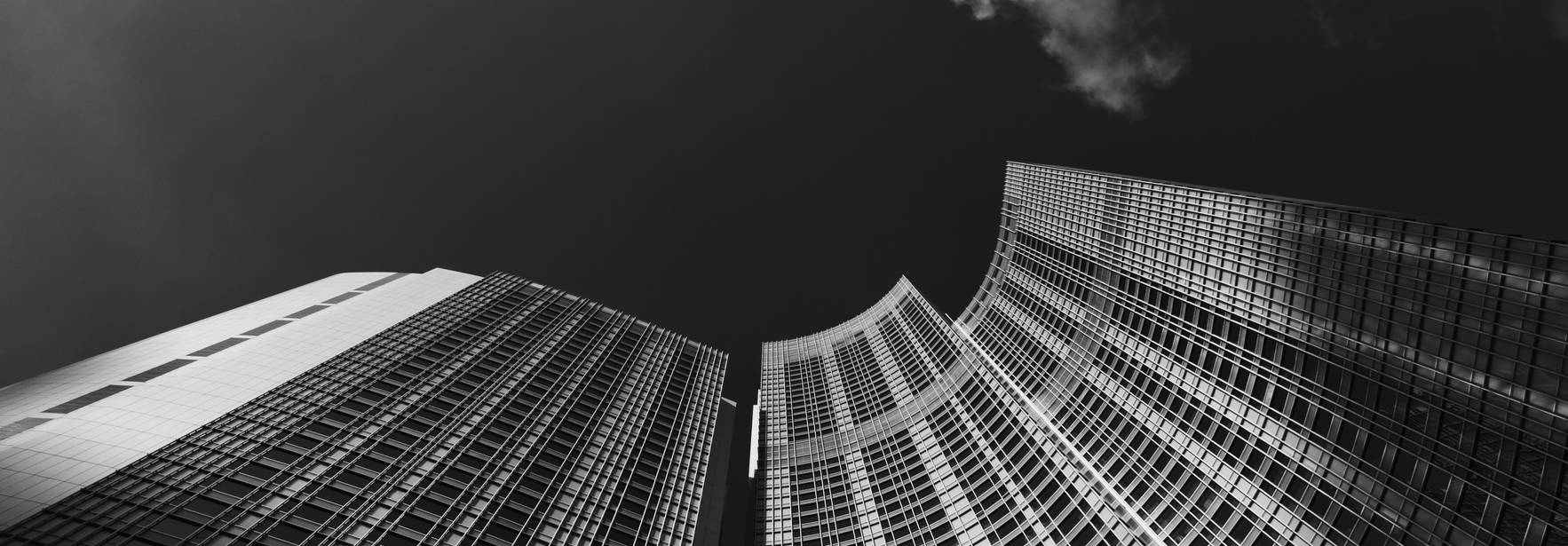 Una vista en ángulo bajo de edificios altos reflejando la luz del sol en un cielo nublado.
