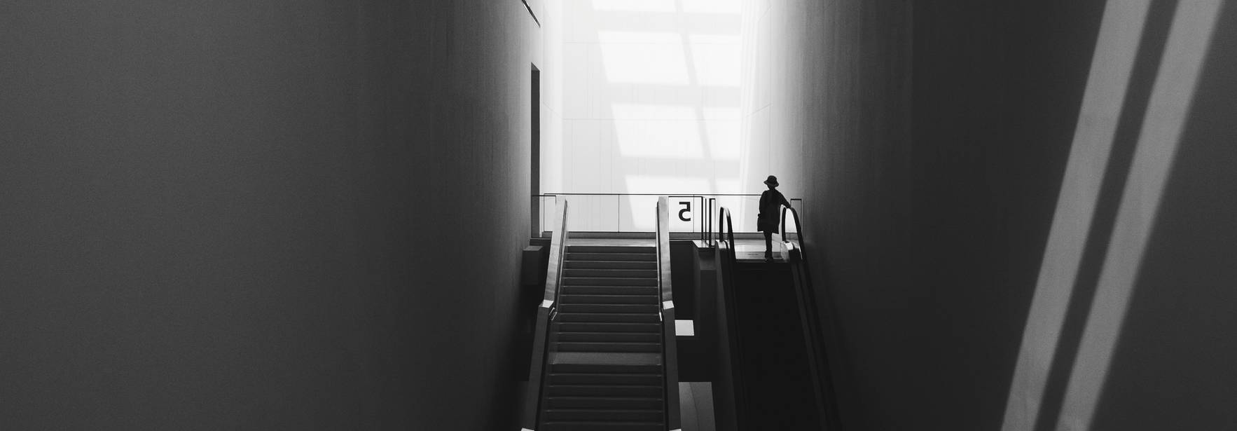 Una persona desciende por una escalera en un espacio iluminado por la luz natural que entra a través de una ventana.