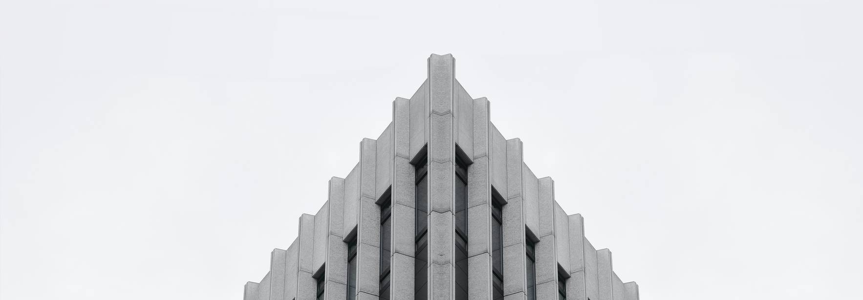 La imagen muestra la parte superior de un edificio moderno con un diseño geométrico y líneas rectas.