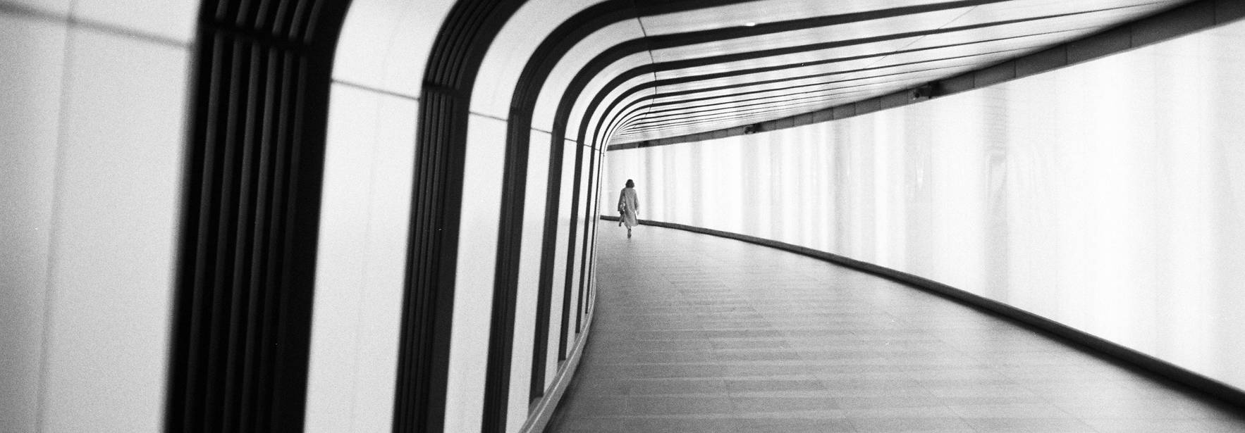 Pasillo moderno y minimalista con un solo individuo al fondo.