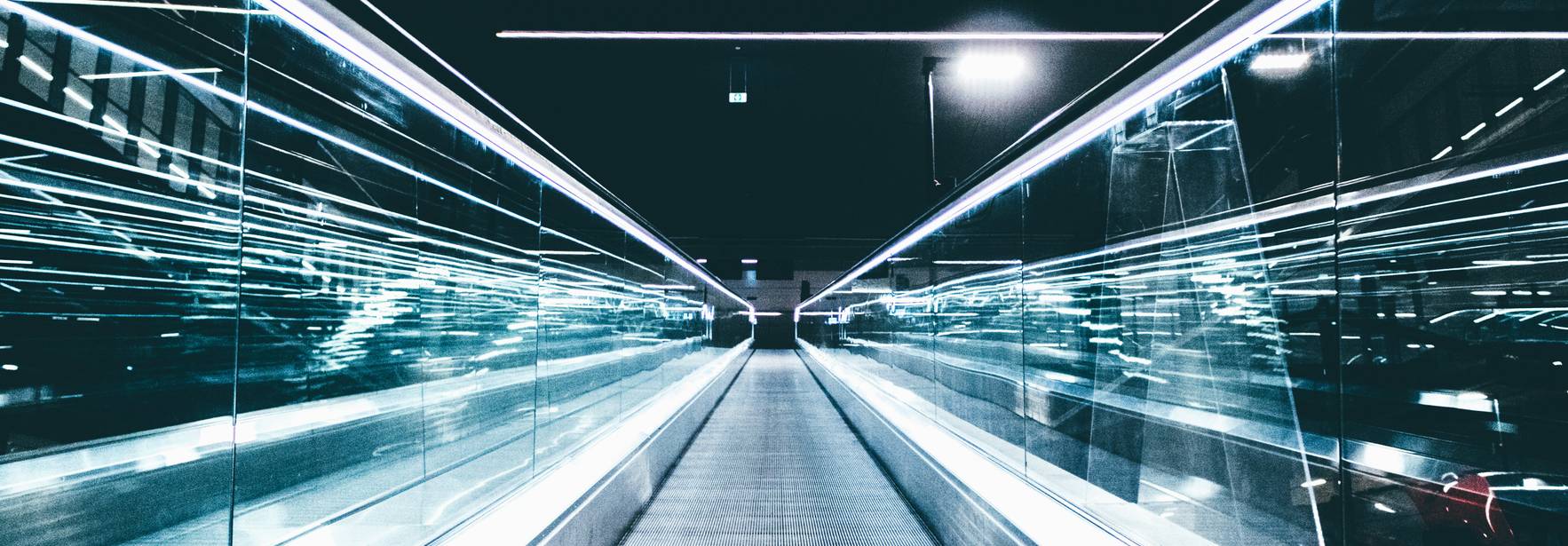 Un pasillo iluminado con luces brillantes y reflejos en un entorno moderno.