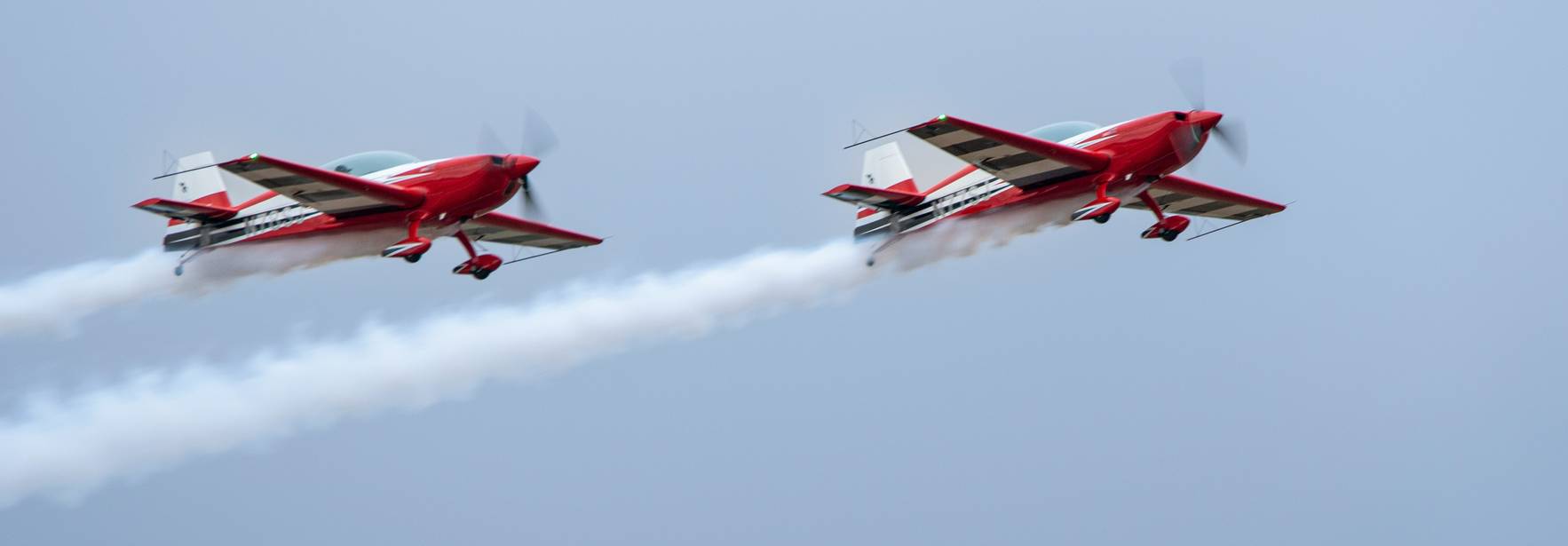 Dos aviones rojos realizando acrobacias en el cielo.