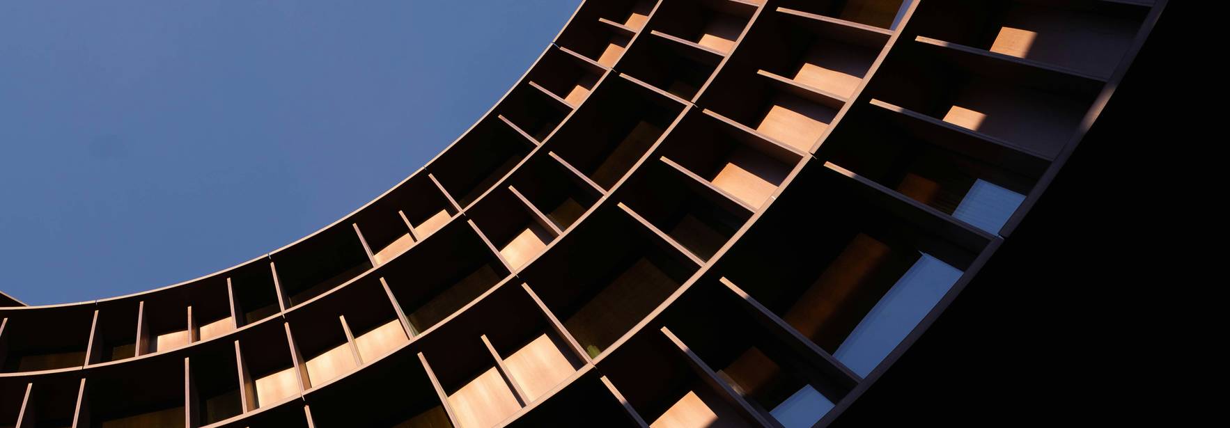 Vista en ángulo bajo de un edificio moderno con ventanas que crean un patrón circular.