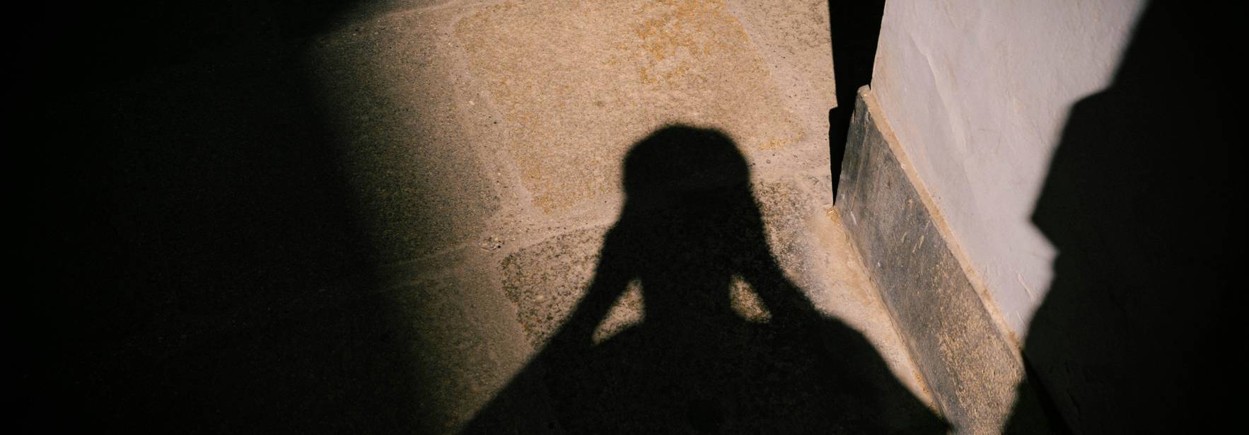La imagen muestra la sombra de una persona proyectada sobre el suelo en un entorno iluminado.