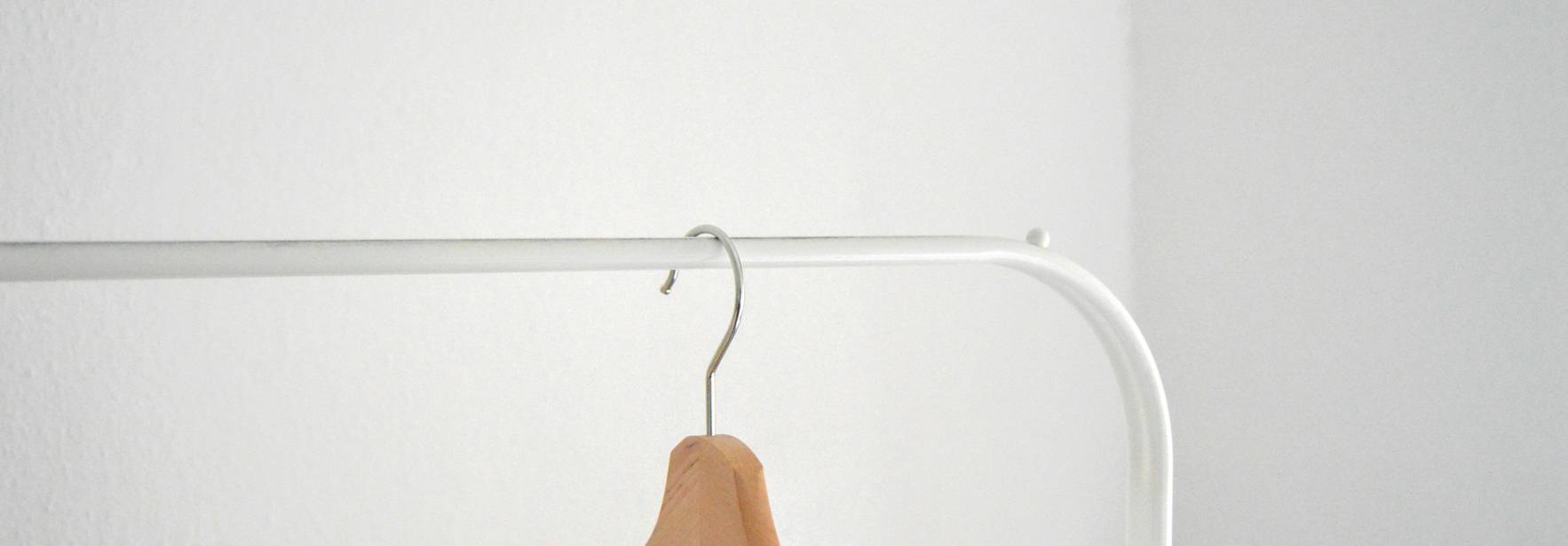 La imagen muestra una camiseta blanca colgada en un perchero de color blanco.