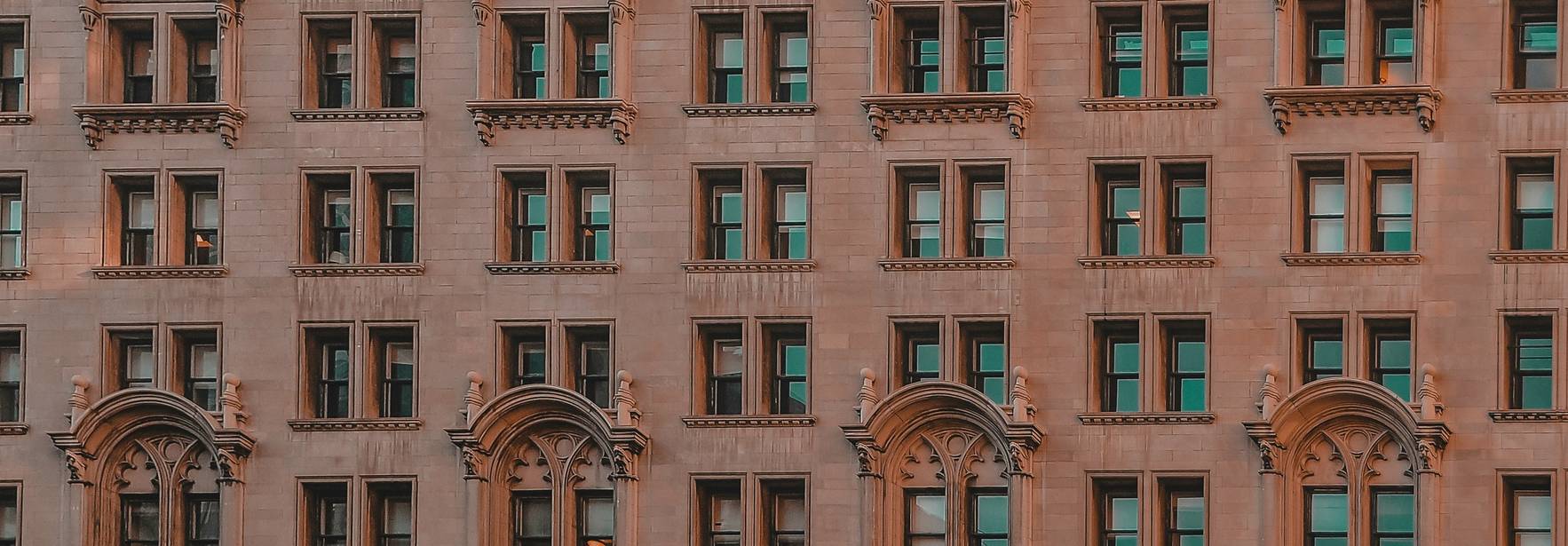 Una fachada de edificio con una serie de ventanas simétricas y detalles arquitectónicos.