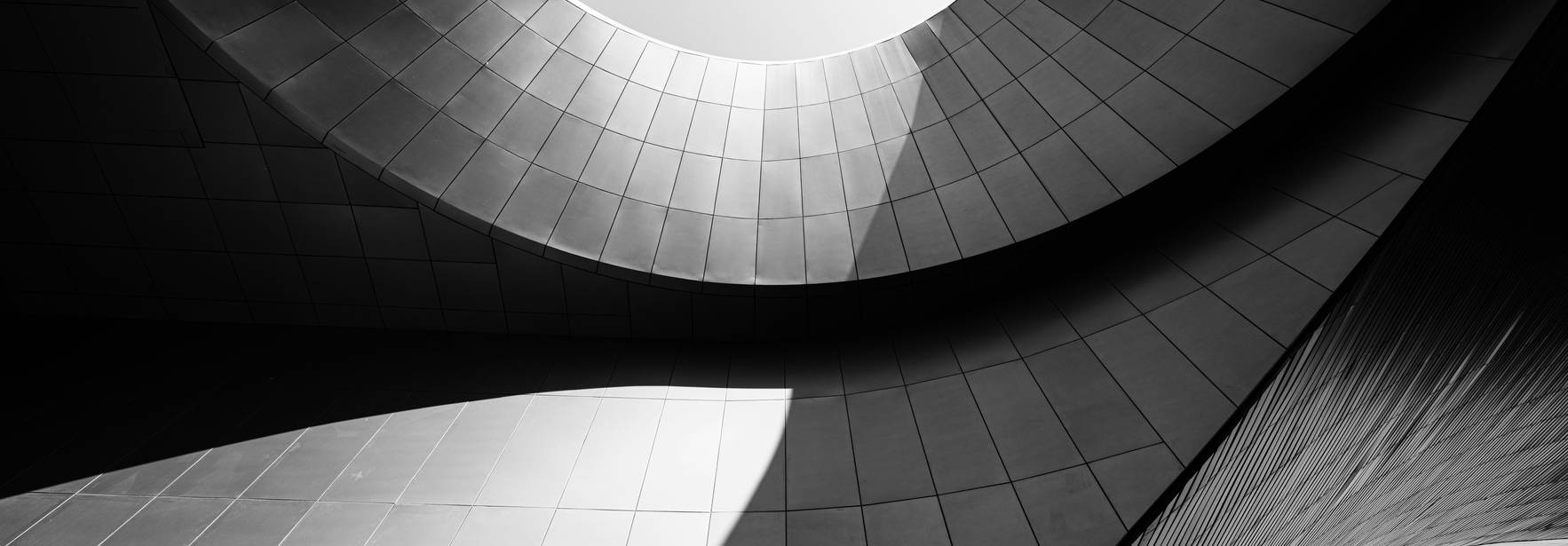 Una vista arquitectónica abstracta en blanco y negro que muestra estructuras curvas y geométricas.