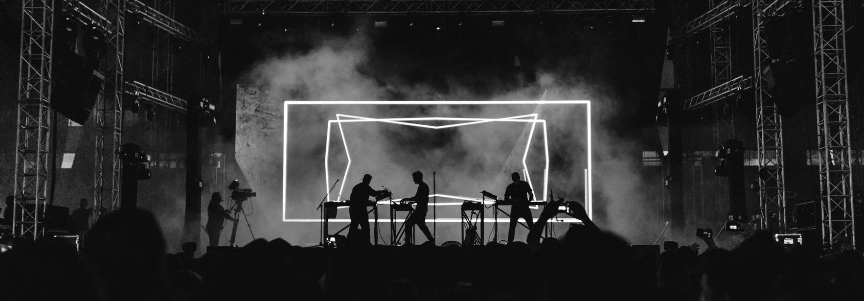 Una presentación musical en un escenario iluminado con efectos visuales en blanco y negro.