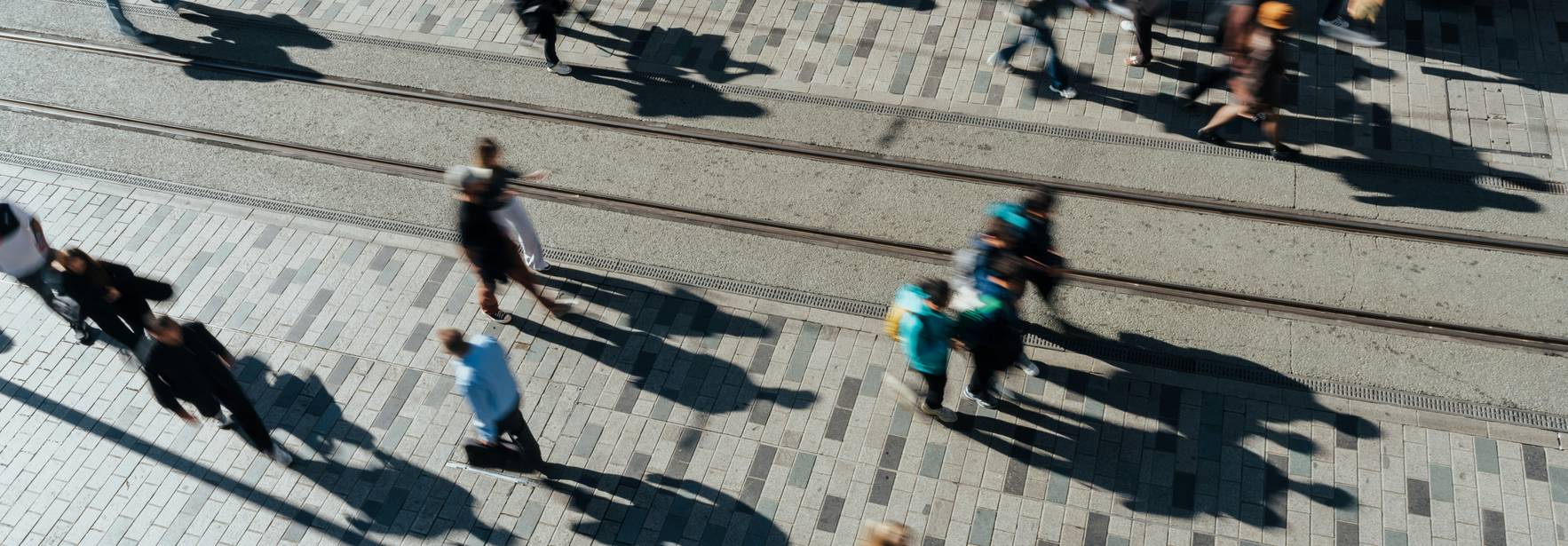Una vista aérea de una multitud de personas caminando por una acera sobre un pavimento de adoquines.
