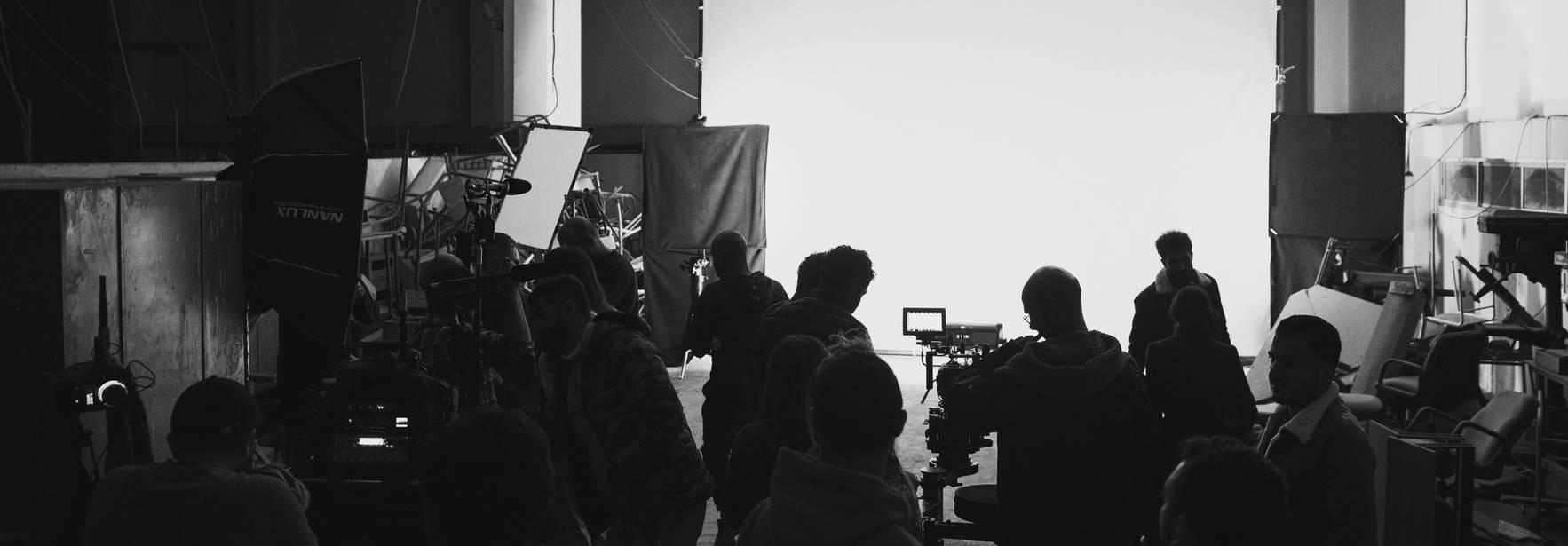 Un grupo de personas trabaja en un set de filmación iluminado por un fondo claro.