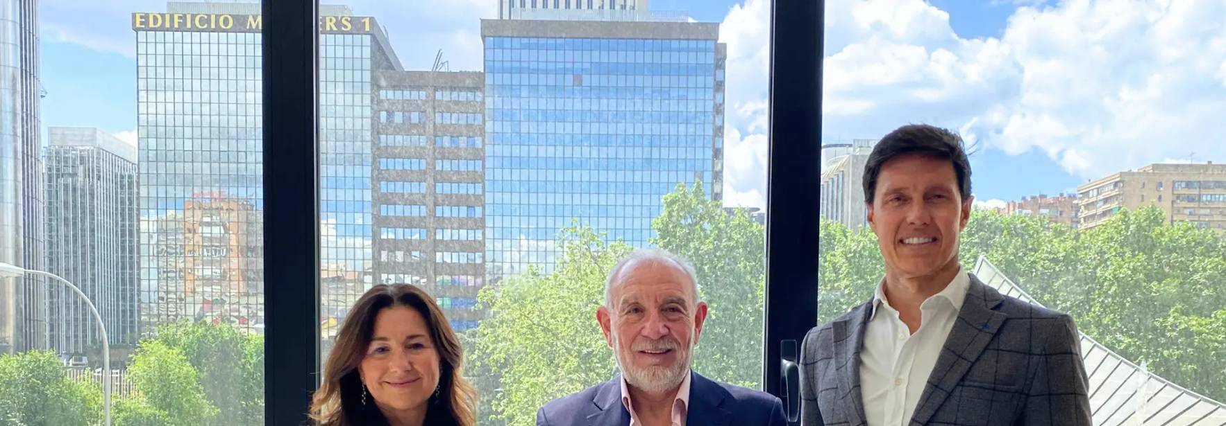 Tres personas posan en un espacio interior con un fondo de ciudad y edificios modernos.