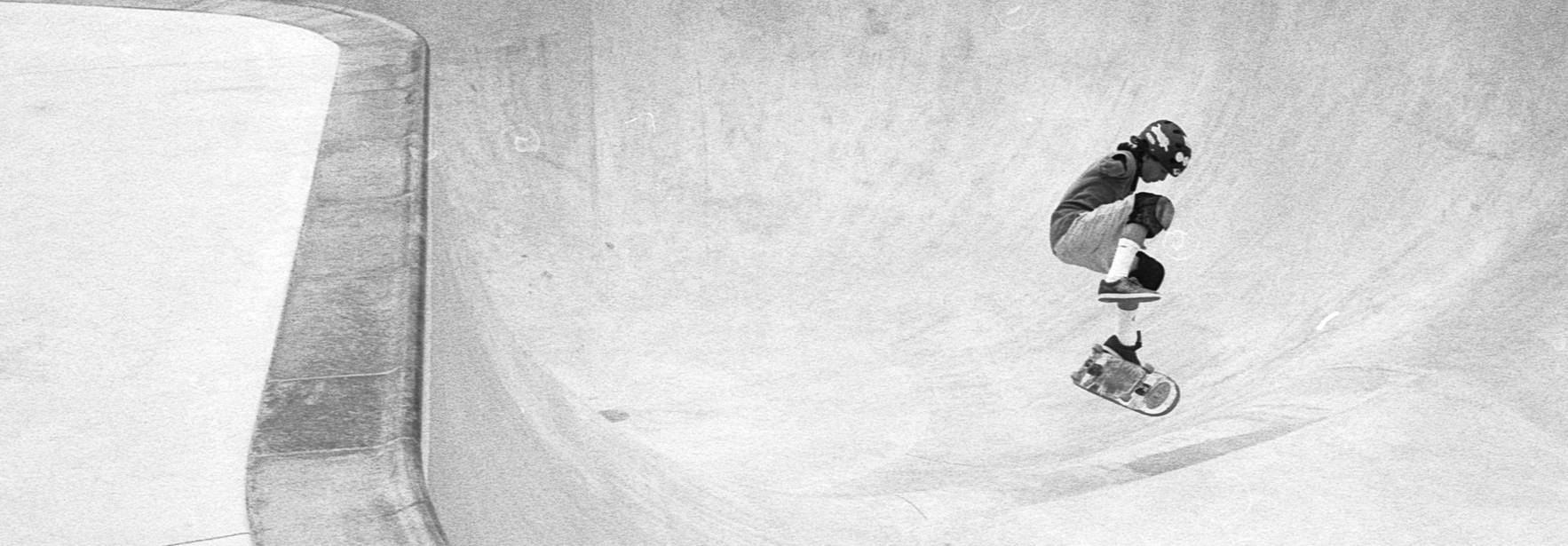 Un skater realiza un truco en un bowl de patinaje en una imagen en blanco y negro.