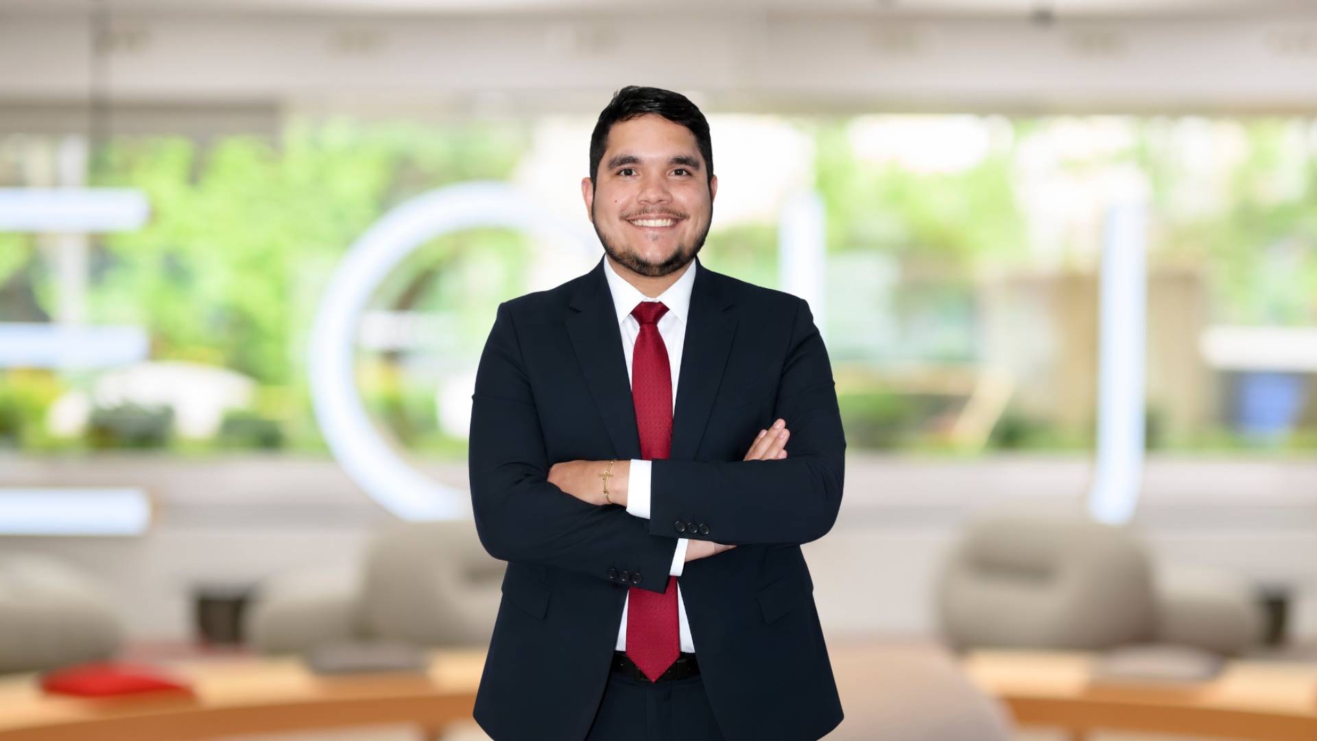 Un hombre de pie sonriente en un entorno de oficina moderno.