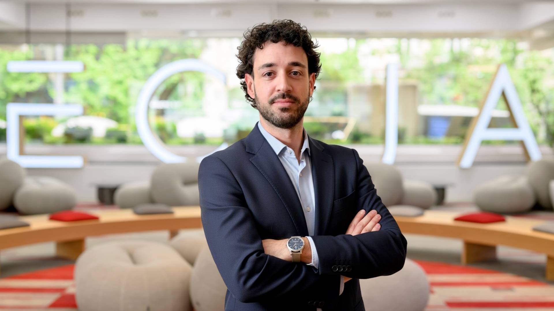 Un hombre con traje de negocios se encuentra de pie en un ambiente moderno y empresarial.