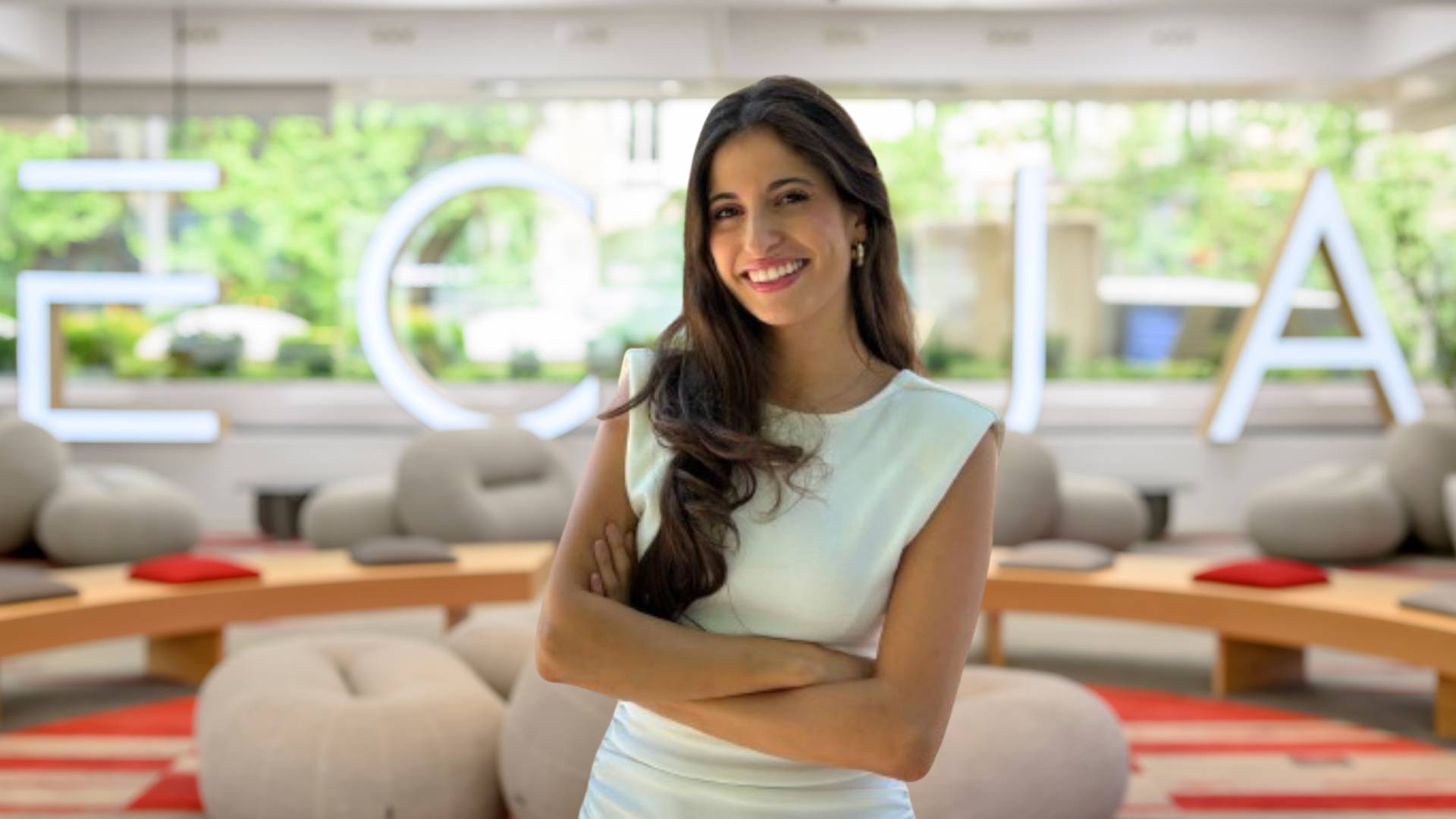 Una mujer sonriente vestidos de blanco en un ambiente moderno y luminoso.