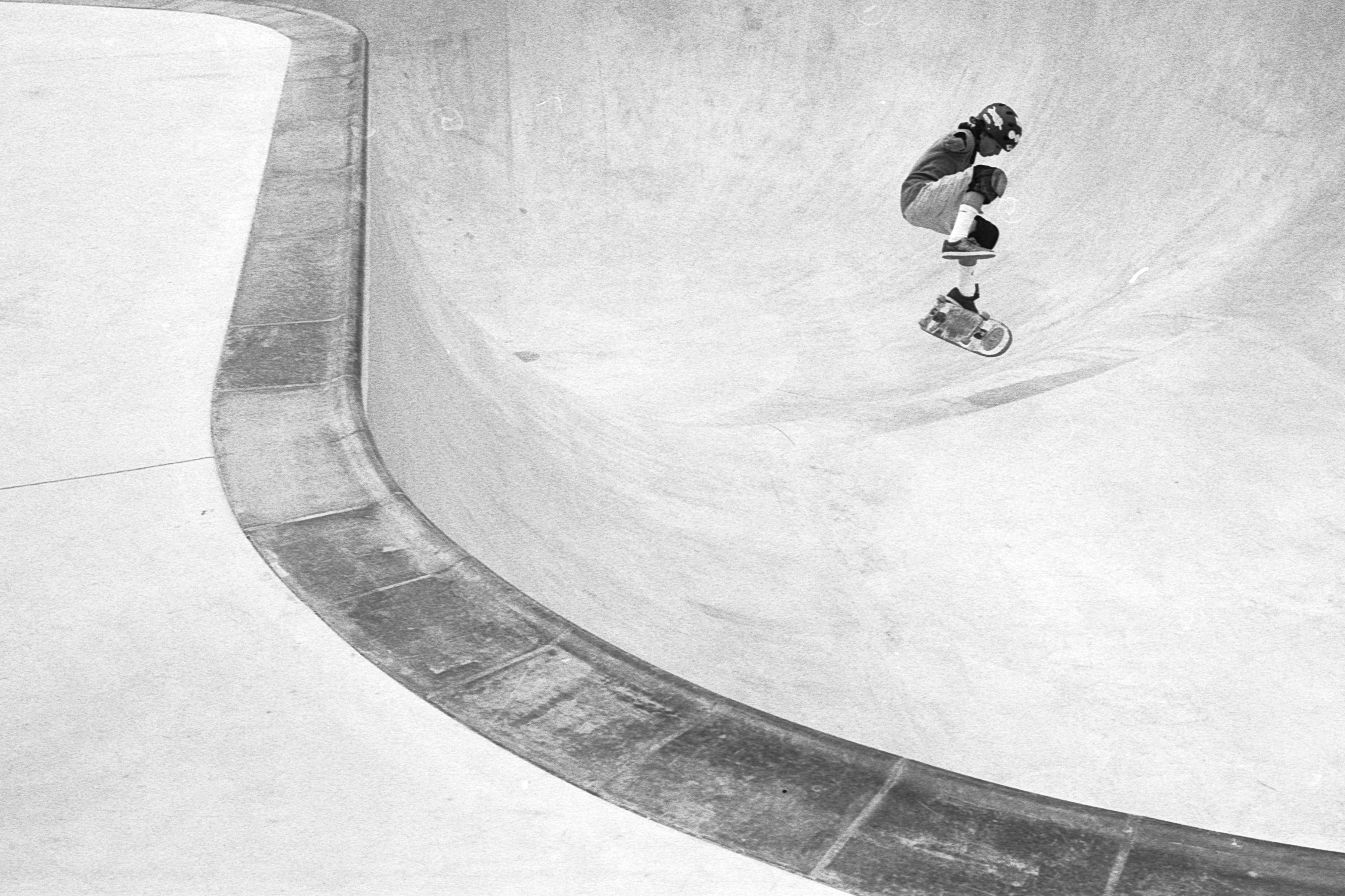 Un skater realiza un truco en un bowl de patinaje en una imagen en blanco y negro.