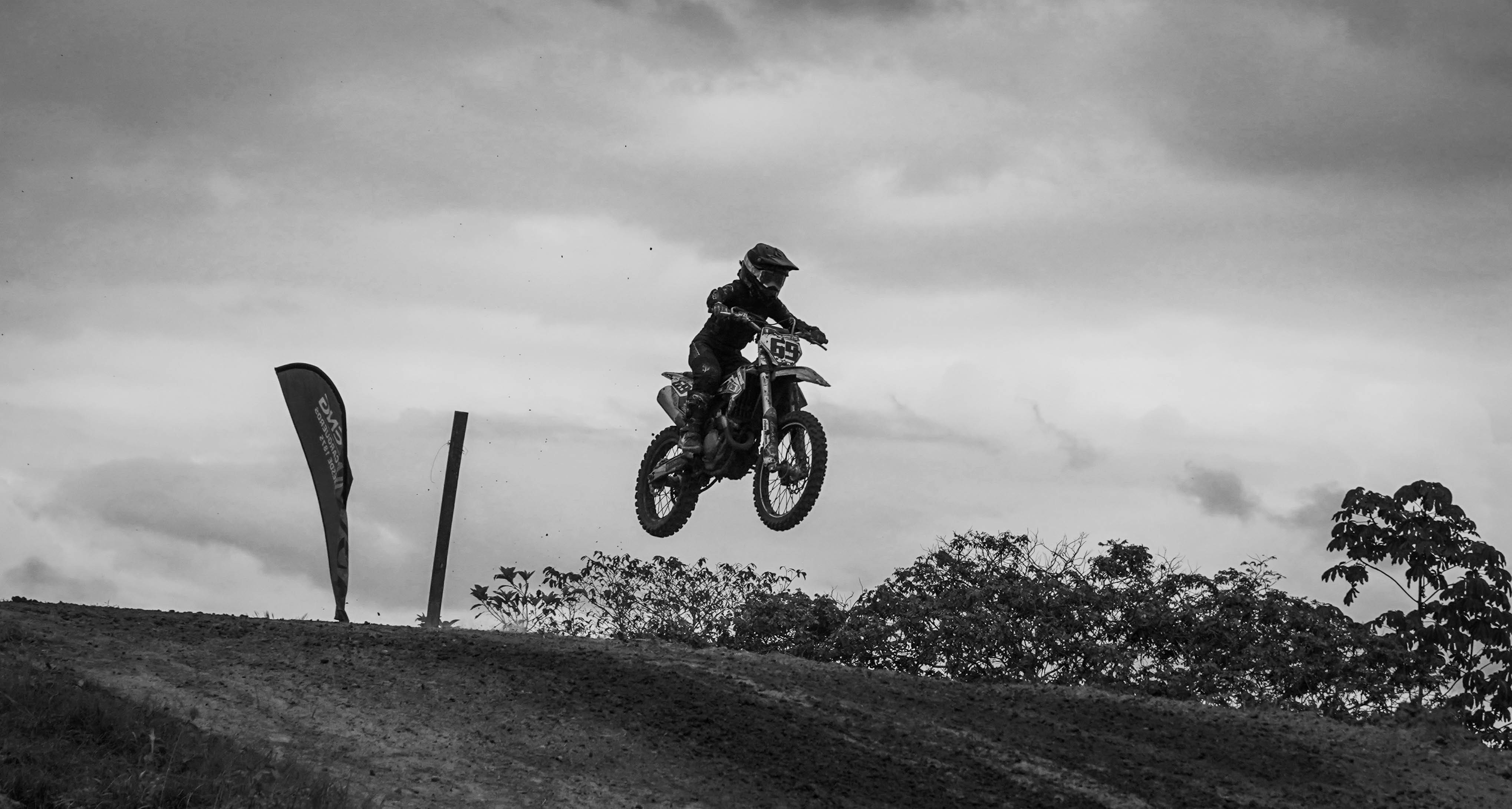 Un motociclista realiza un salto en una pista de motocross en un entorno natural.